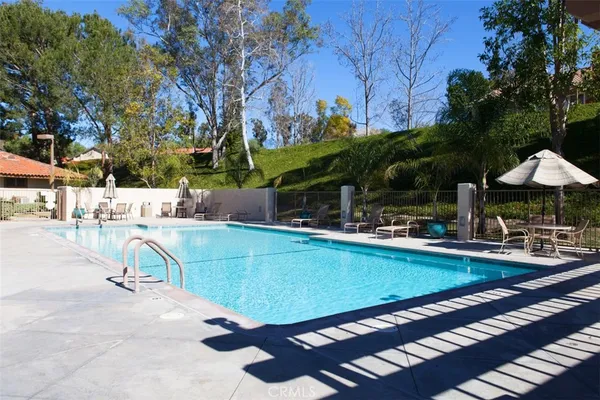 a view of a swimming pool with a lawn chairs under an umbrella