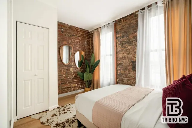 a bedroom with a bed and a window with a mirror