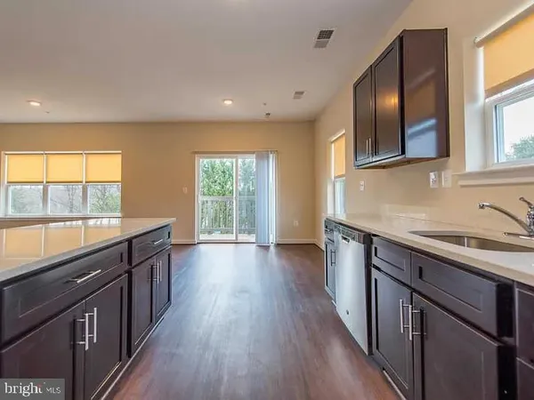 a kitchen with stainless steel appliances granite countertop wooden cabinets a stove a sink and a large window