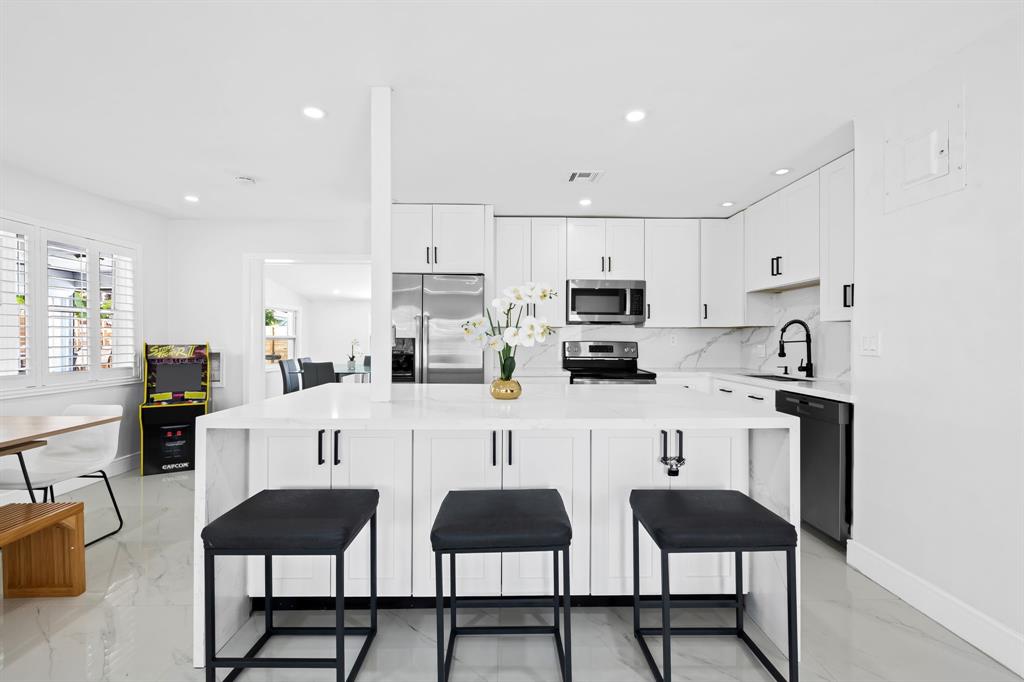 865 Northeast 23rd Terrace Pompano Beach, FL 33062 - Photo 12 of 33 a kitchen with stainless steel appliances a stove a table and chairs in it