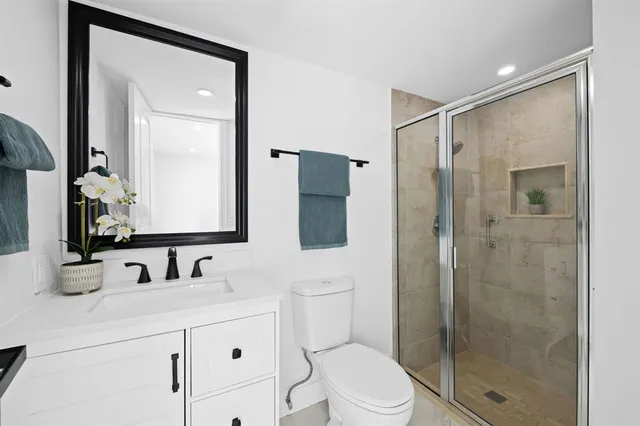 a bathroom with a shower sink vanity mirror and toilet