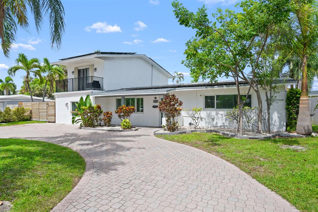 865 Northeast 23rd Terrace Pompano Beach, FL 33062 - Photo 3 of 33 a front view of a house with a yard and a garage