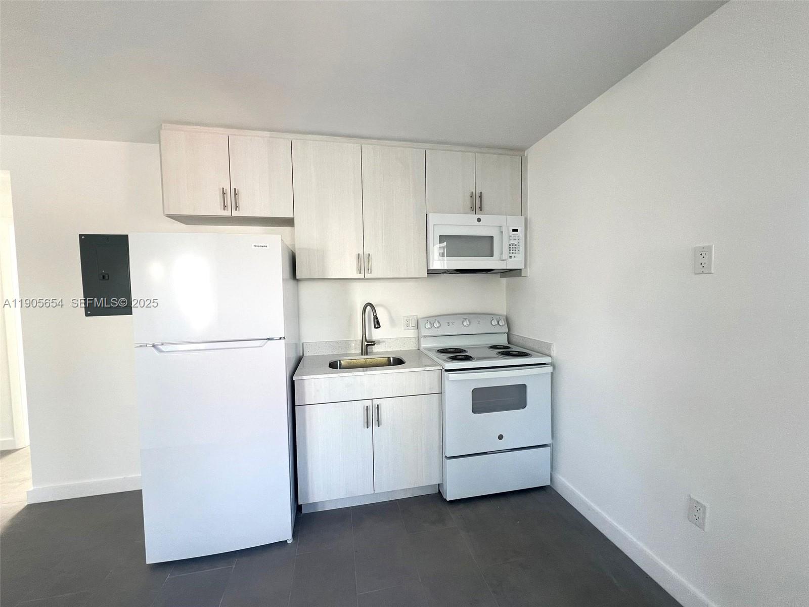 1541 Northwest 1st Place, Unit 4 Miami, FL 33136 - Photo 2 of 6 a kitchen with a white cabinets and white appliances