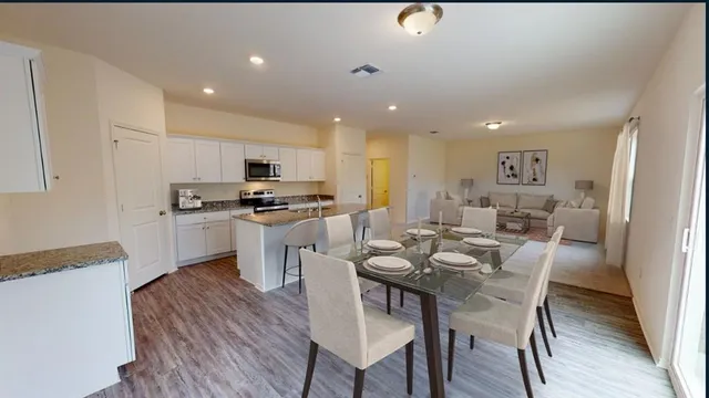 a kitchen with a dining table chairs and refrigerator