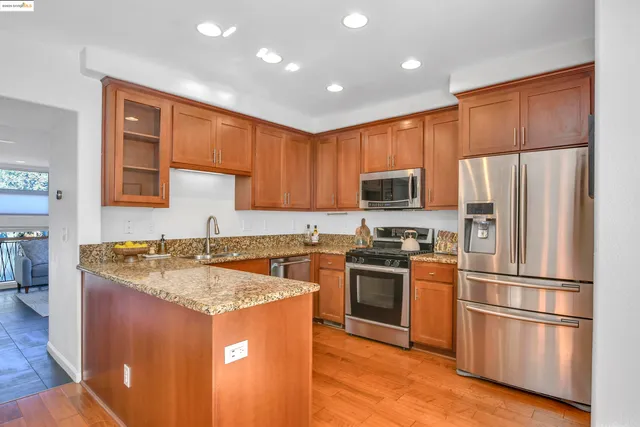 a kitchen with granite countertop a stove top oven a sink dishwasher and cabinets with wooden floor