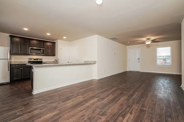a view of kitchen with granite countertop stainless steel appliances counter space and wooden floor