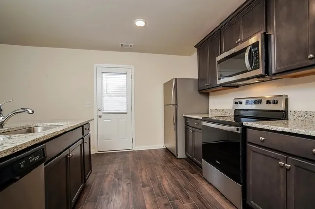 a kitchen with stainless steel appliances granite countertop a refrigerator microwave and sink