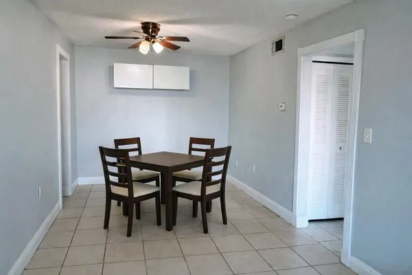 a dining room with furniture and a chandelier fan