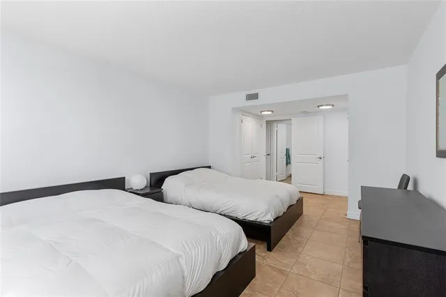 a spacious bedroom with two beds and a lamp