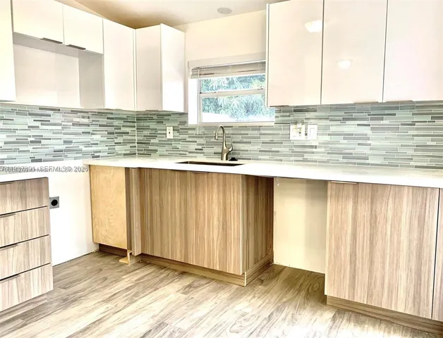 a view of a kitchen with wooden floor and a window