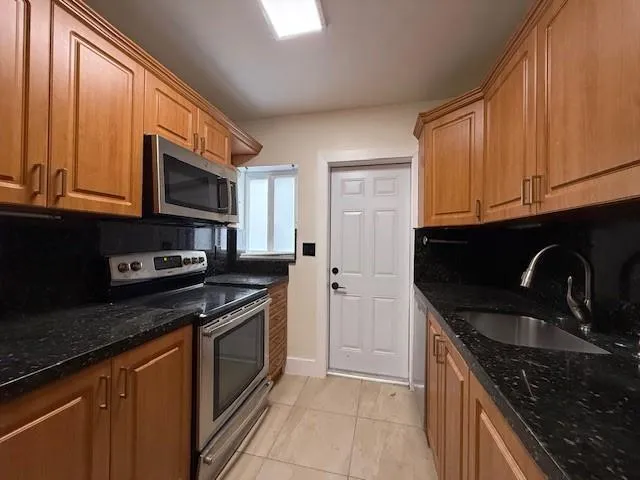 a kitchen with granite countertop wooden cabinets stainless steel appliances and a sink
