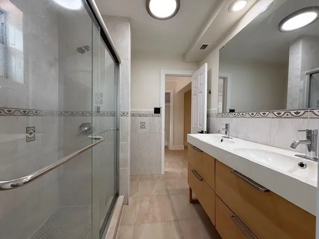 a spacious bathroom with a double vanity sink a mirror and a shower