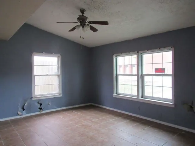 an empty room with a window and a fan