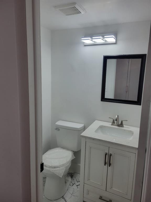 4222 Inverrary Boulevard, Unit 4413 Lauderhill, FL 33319 - Photo 12 of 34 a bathroom with a toilet sink vanity and mirror