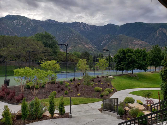 3 Carriagewood Cove, Unit 1088 Sandy, UT 84092 - Photo 72 of 79 Professional tennis courts set against a mountain backdrop, featuring landscaped gardens, manicured lawns, and concrete pathways with modern railings