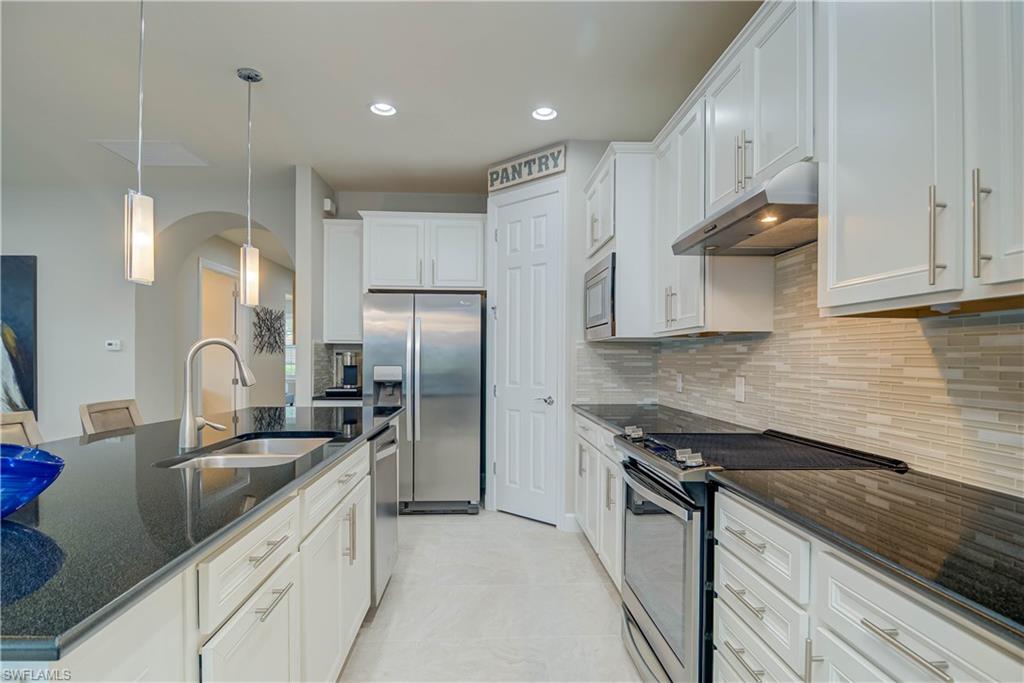 7938 Guadiana Way Ave Maria, FL 34142 - Photo 11 of 37 a kitchen with stainless steel appliances granite countertop a sink a stove and a refrigerator