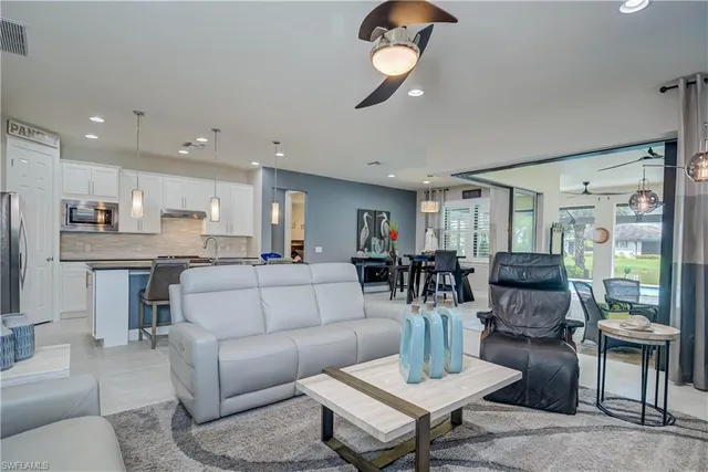 a living room with furniture kitchen view and a chandelier