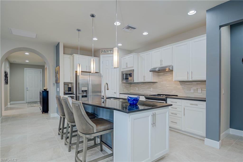 7938 Guadiana Way Ave Maria, FL 34142 - Photo 9 of 37 a kitchen with white cabinets and chairs