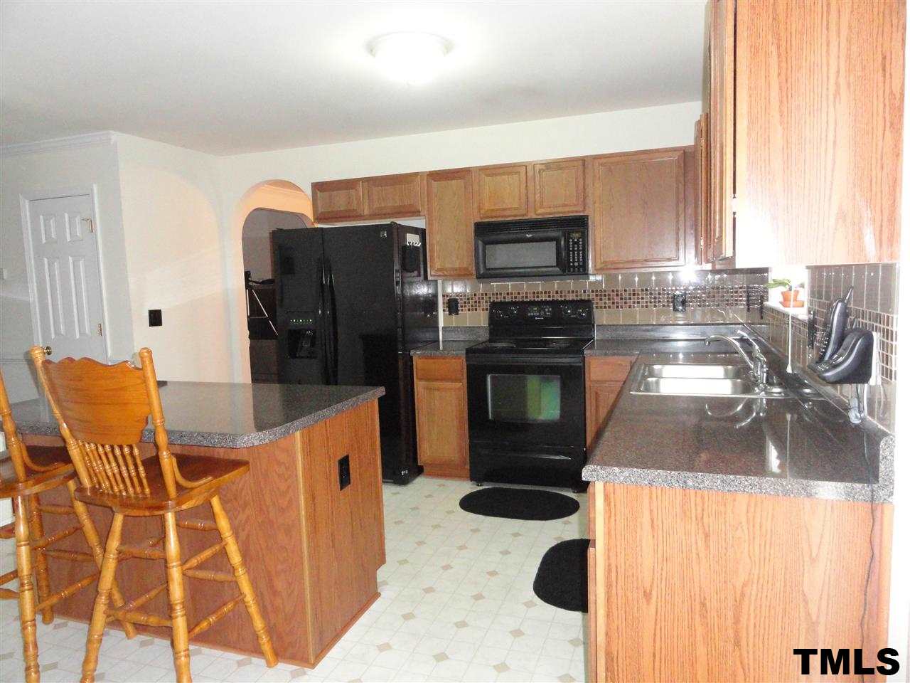 904 Morning Still Court Rolesville, NC 27571 - Photo 7 of 25 a kitchen with stainless steel appliances kitchen island granite countertop a refrigerator and microwave