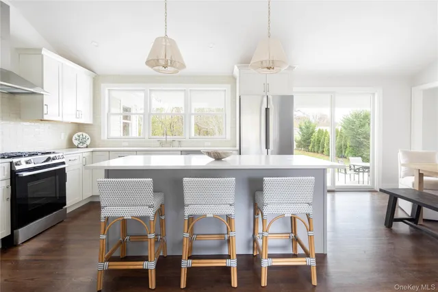 a kitchen with a dining table chairs and large windows