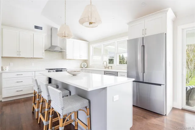 a kitchen with a refrigerator a stove a sink and white cabinets with wooden floor