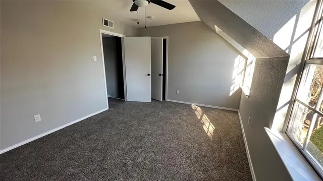 an empty room with windows and fan