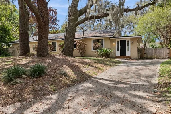 a front view of a house with a garden and trees