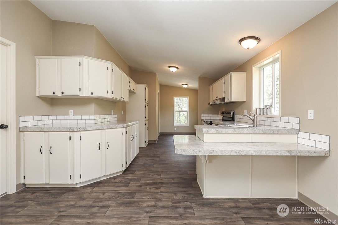 673 Curtis Hill Road, Unit G Chehalis, WA 98532 - Photo 5 of 25 a large white kitchen with granite countertop a stove a sink a refrigerator and white cabinets with wooden floor