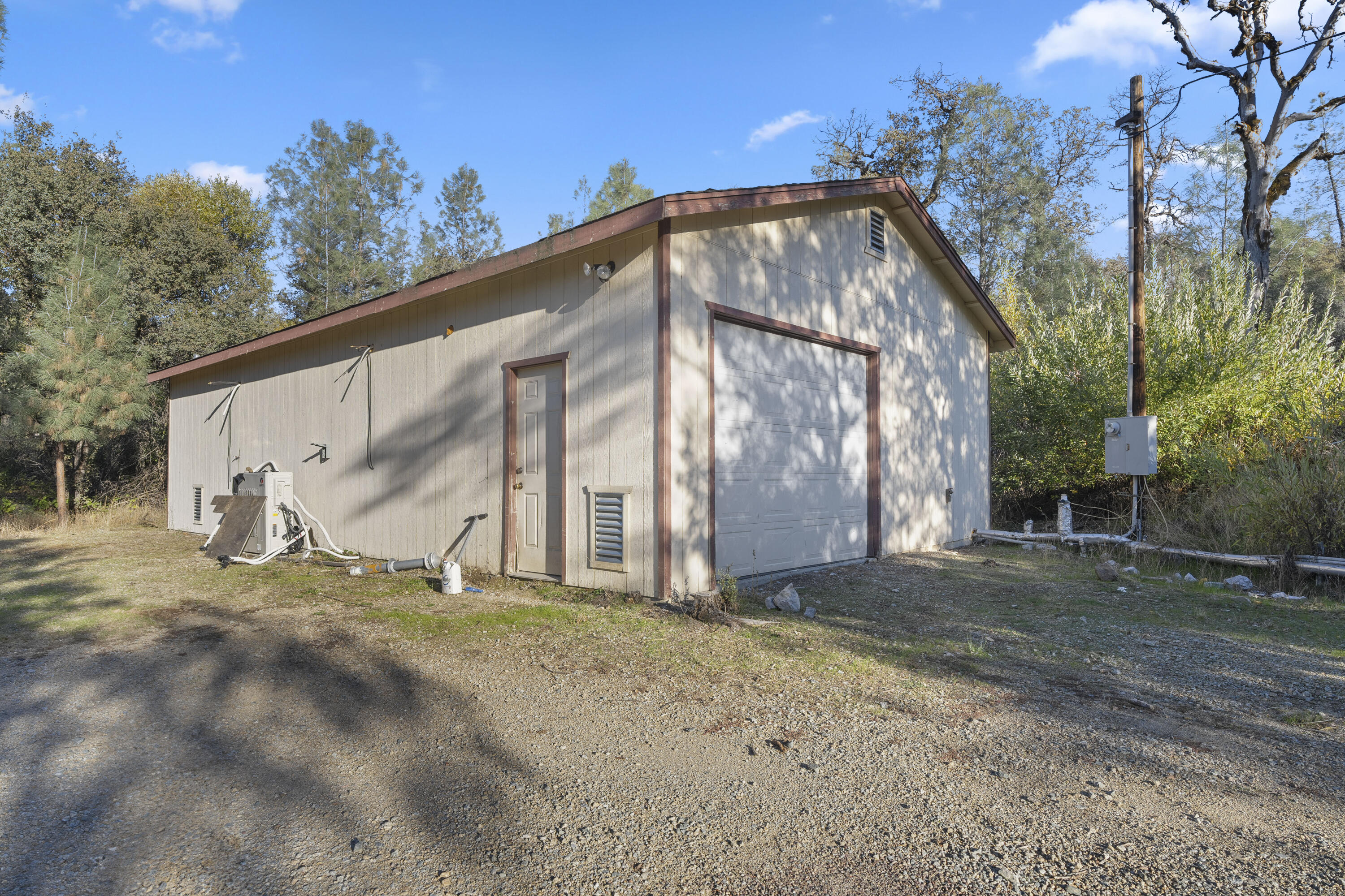 6841 Vista Lavega Road Shingletown, CA 96088 - Photo 41 of 80 a backyard of a house with large trees and covered by side of the house