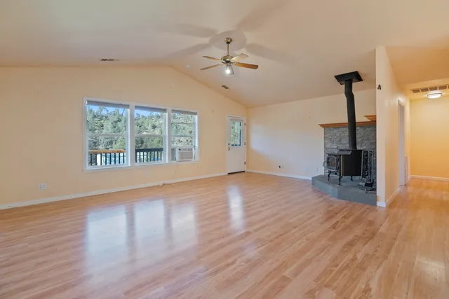 a view of an empty room with a window and wooden floor