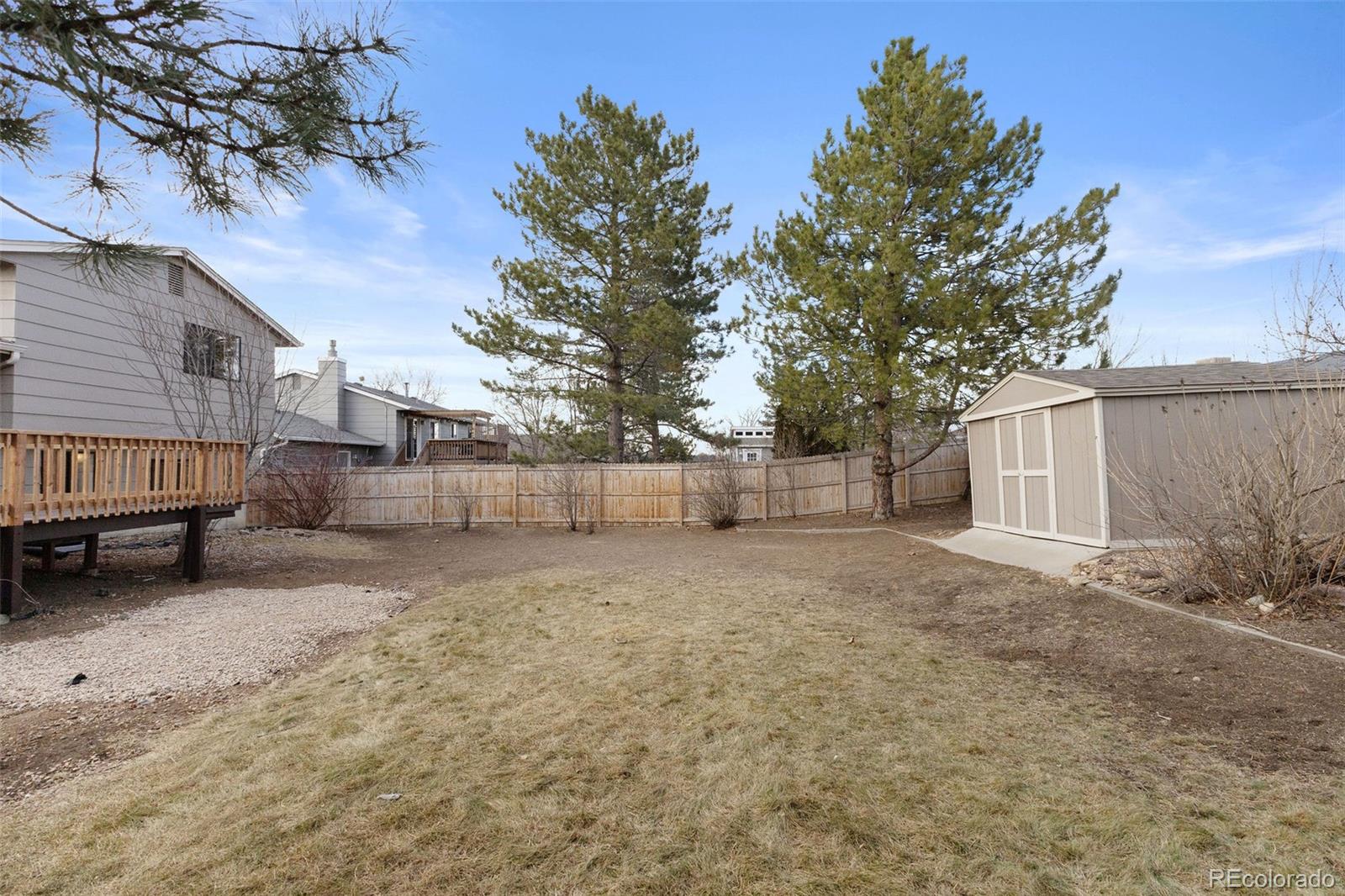 9458 Flower Street Broomfield, CO 80021 - Photo 28 of 30 a view of a backyard with large trees and wooden fence