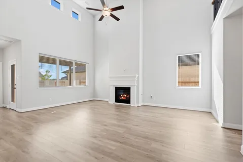 an empty room with wooden floor fan and windows