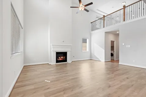 a view of an empty room with wooden floor fireplace and a window