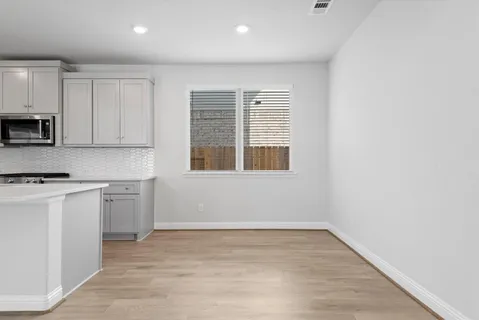 a kitchen with stainless steel appliances white cabinets a sink a stove a refrigerator and white cabinets