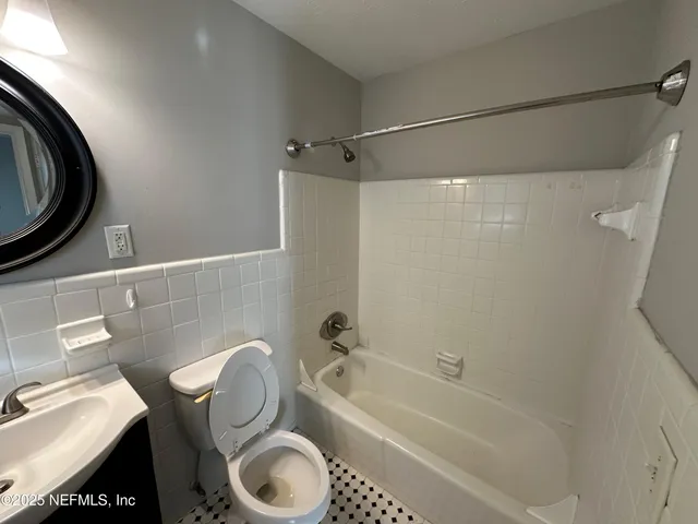 a bathroom with a toilet mirror vanity and a sink