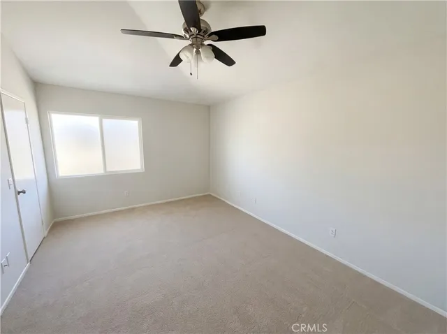 an empty room with a window and a fan