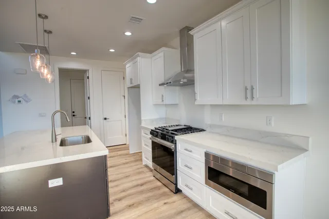 a kitchen with a sink a stove a refrigerator and white cabinets