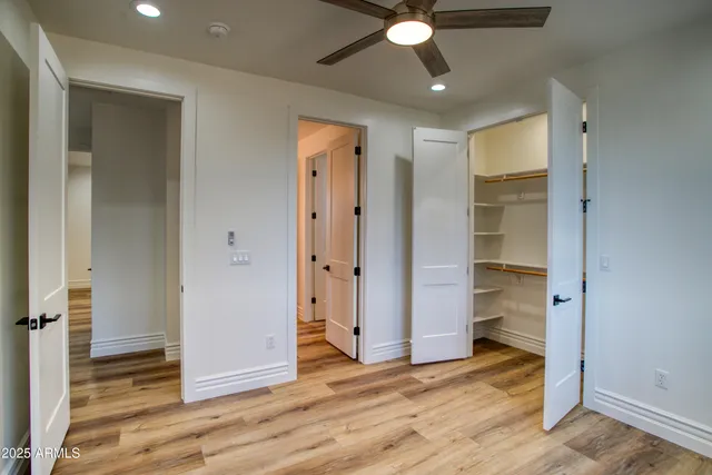 a view of empty room with wooden floor and fan