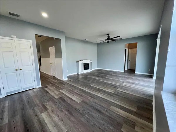a view of a livingroom with a fireplace a ceiling fan and wooden floor