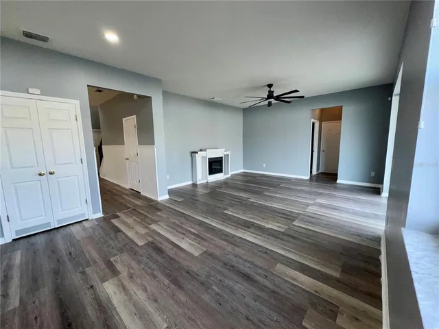 a view of a livingroom with a fireplace a ceiling fan and wooden floor