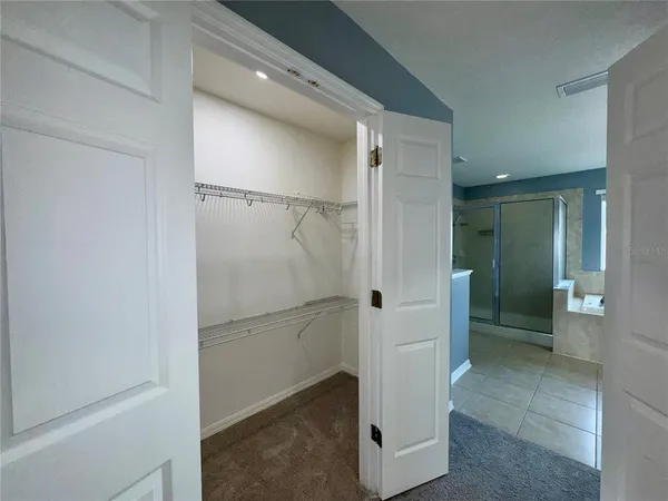 an empty room with closet and a ceiling fan