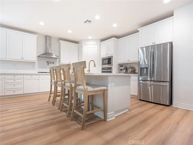 a kitchen with stainless steel appliances a refrigerator a stove top oven and white cabinets