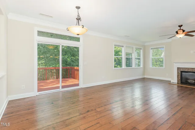 a view of an empty room with wooden floor fireplace and a window
