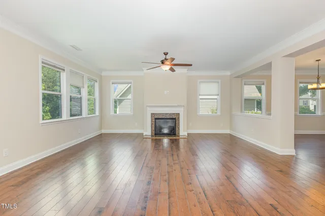 a view of an empty room with wooden floor windows and a chandelier