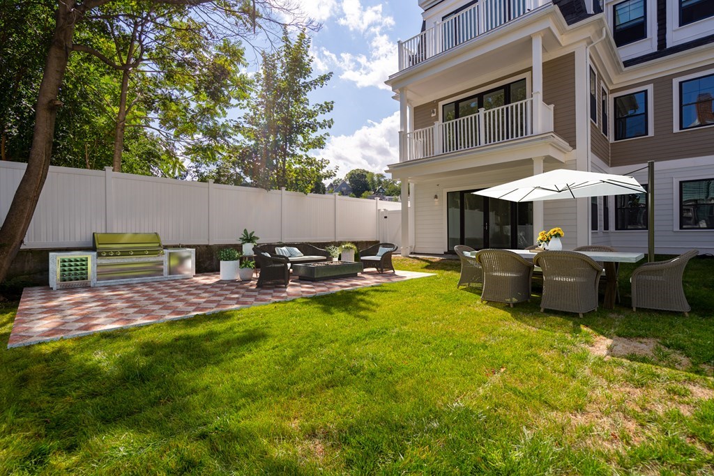 54 Pleasant Street, Unit 5 Boston, MA 02125 - Photo 23 of 23 a view of a backyard with table and chairs under an umbrella