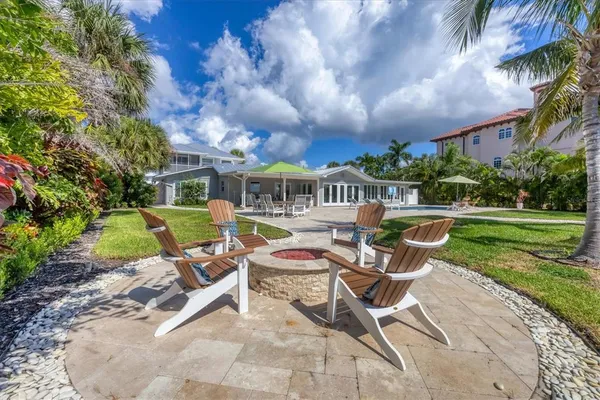 a view of a swimming pool with lawn chairs potted plants and palm trees