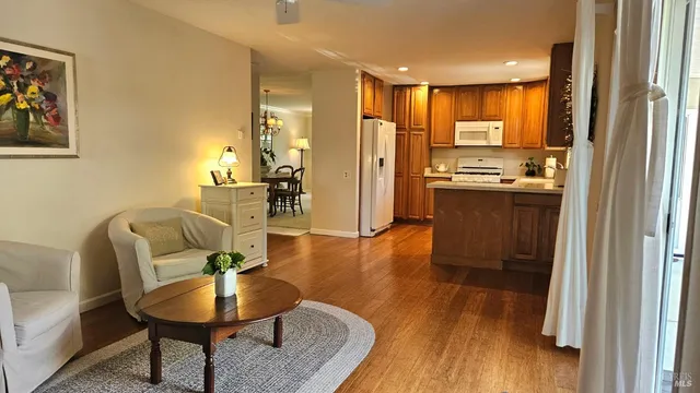 a living room with stainless steel appliances kitchen island granite countertop furniture and a wooden floor