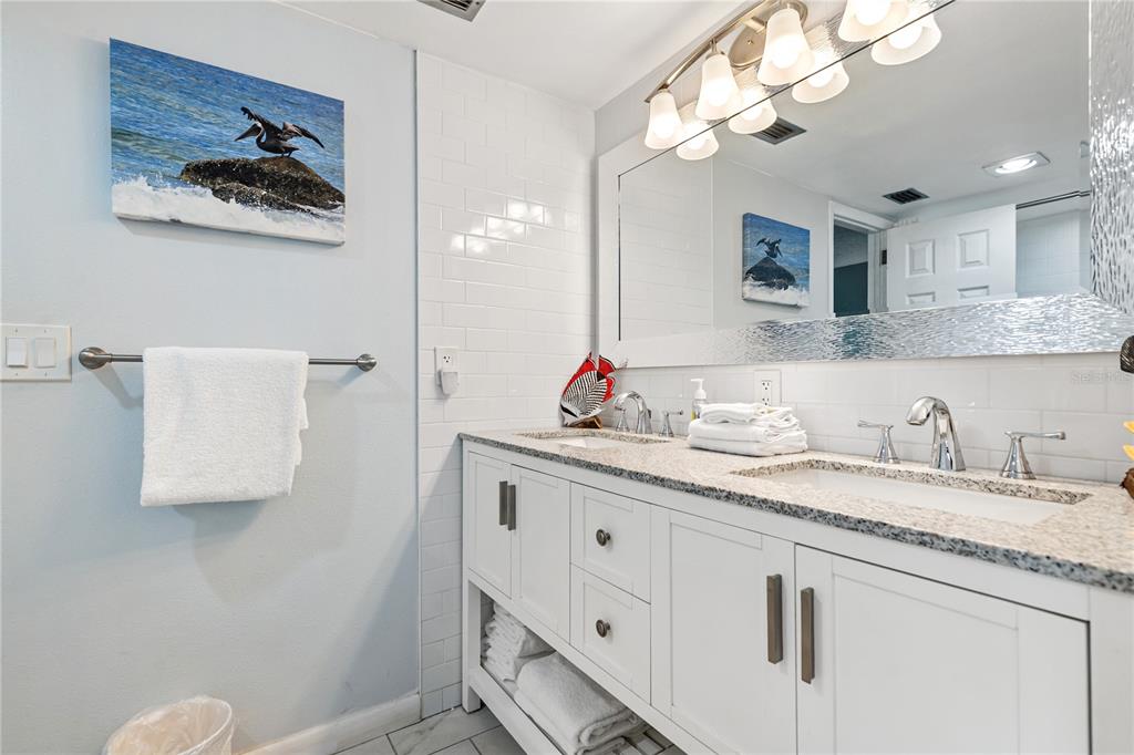 230 Medallion Boulevard, Unit E Madeira Beach, FL 33708 - Photo 16 of 35 a bathroom with a granite countertop sink a toilet and a mirror