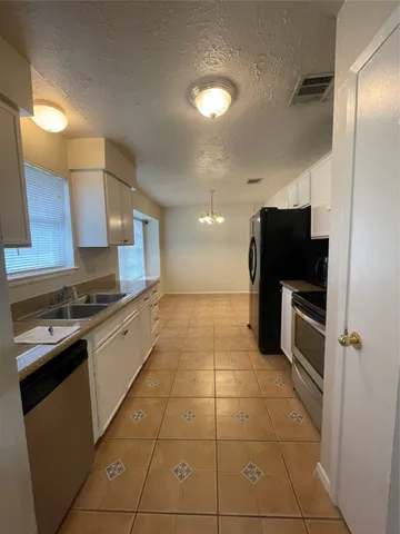 a kitchen with granite countertop a refrigerator and a stove top oven