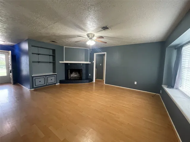 a view of an empty room with a fireplace and a window